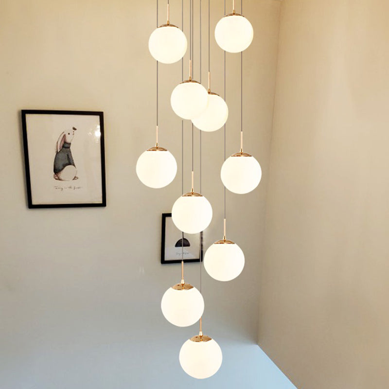 Plafonnier minimaliste doré à plusieurs suspensions avec bulles en verre crème et suspension d'escalier en verre blanc
