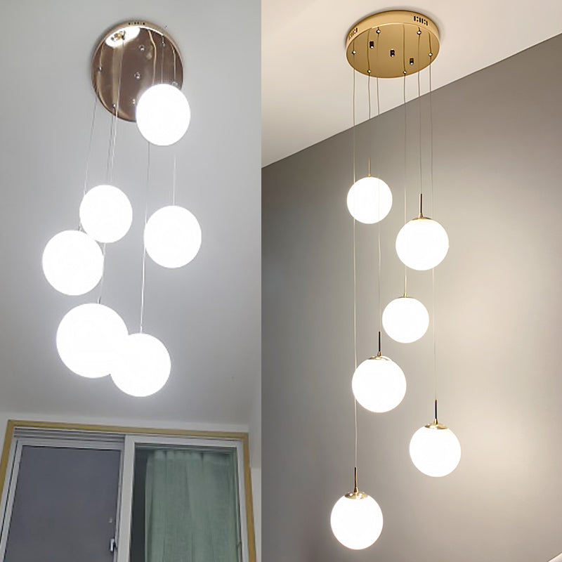 Plafonnier minimaliste doré à plusieurs suspensions avec bulles en verre crème et suspension d'escalier en verre blanc