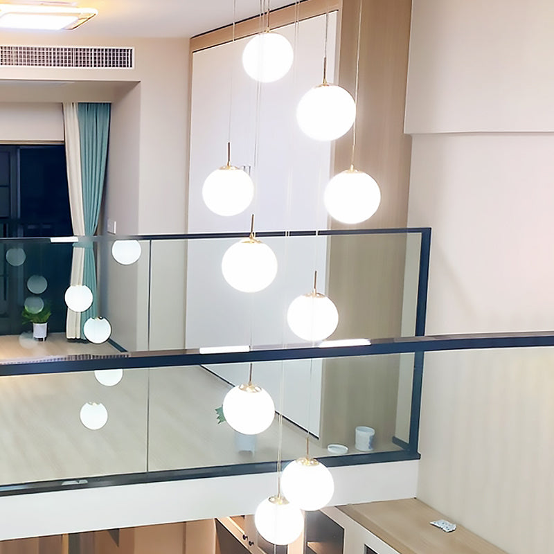 Plafonnier minimaliste doré à plusieurs suspensions avec bulles en verre crème et suspension d'escalier en verre blanc