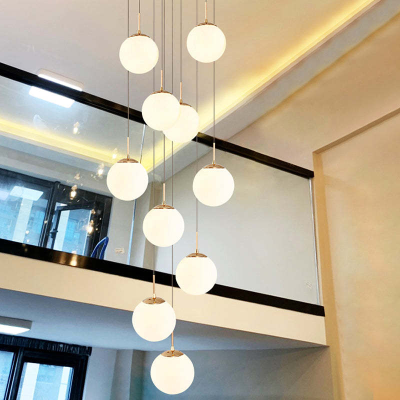 Plafonnier minimaliste doré à plusieurs suspensions avec bulles en verre crème et suspension d'escalier en verre blanc